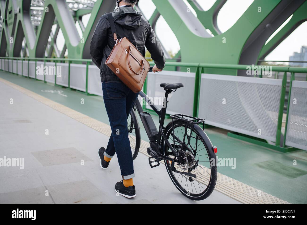 Vista posteriore del commuter uomo d'affari sulla strada per il lavoro, spingere la bicicletta, concetto di stile di vita sostenibile. Foto Stock