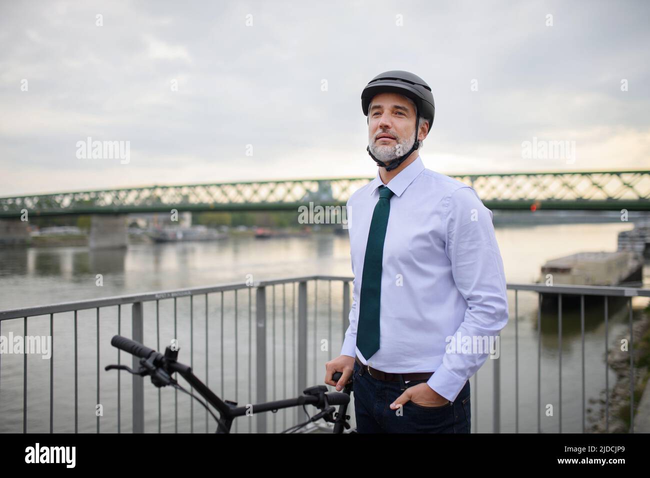 Uomo d'affari commuter sulla strada del lavoro, in piedi sul ponte e con moto, concetto di stile di vita sostenibile. Foto Stock