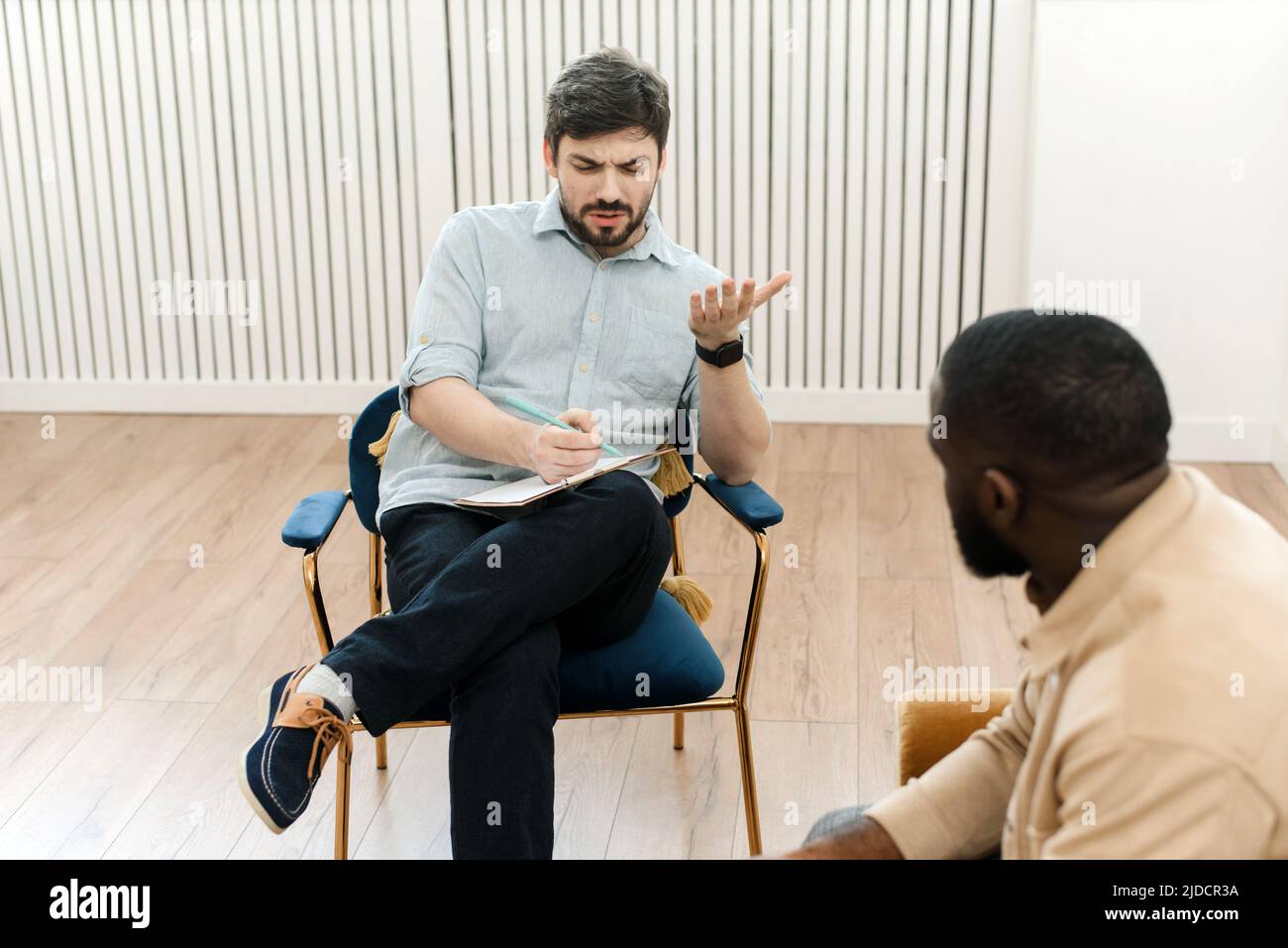 Un paziente di sesso maschile nero che subisce una sessione di psicoterapia con un consulente in una clinica di salute mentale. Il giovane con problemi emotivi si consulta Foto Stock