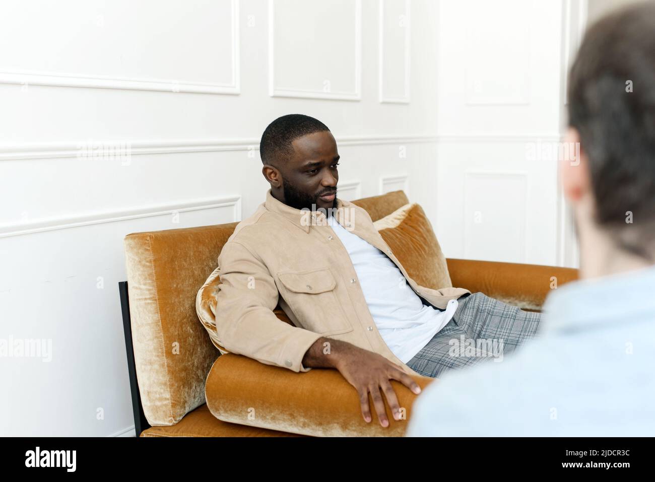 Un paziente di sesso maschile nero che subisce una sessione di psicoterapia con un consulente in una clinica di salute mentale. Il giovane con problemi emotivi si consulta Foto Stock