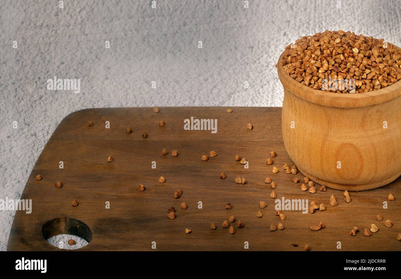 Primo piano foto un grano saraceno in una tazza di legno su un tagliere di legno Foto Stock