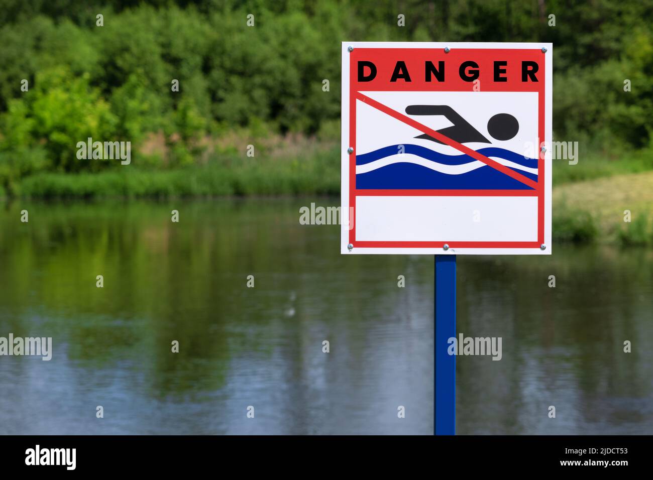 Cartello per nuotare, sulla riva del fiume. Cartello sulla riva del lago artificiale: È vietato nuotare. Erba e giorno d'estate. Il segno vi informa che Foto Stock