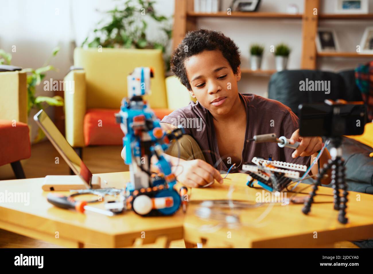 Un ragazzino educato che si registra per un vlog e fa un robot. Educazione all'elettronica e all'intelligenza artificiale. Foto Stock