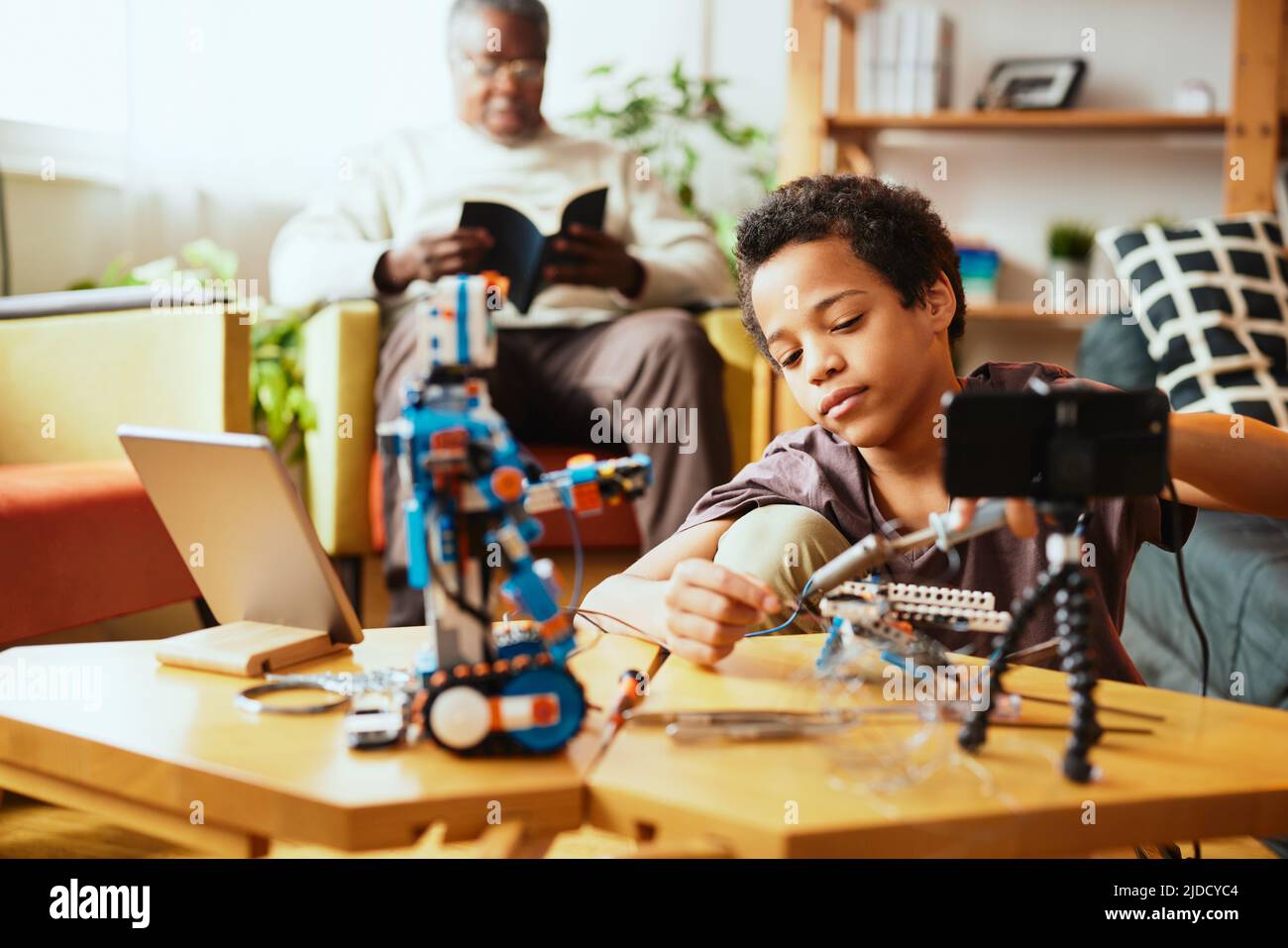 Un ragazzino educato che si registra per un vlog e fa un robot. Educazione all'elettronica e all'intelligenza artificiale. Foto Stock