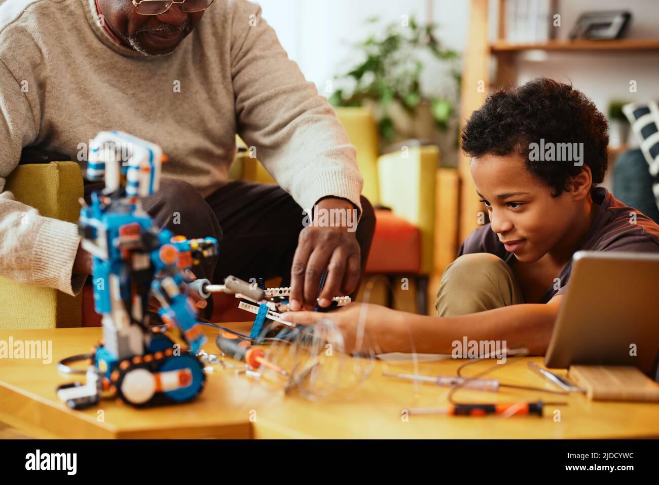 Un nonno e un nipote che fanno insieme un robot a casa. Formazione in robotica ed elettronica. Foto Stock