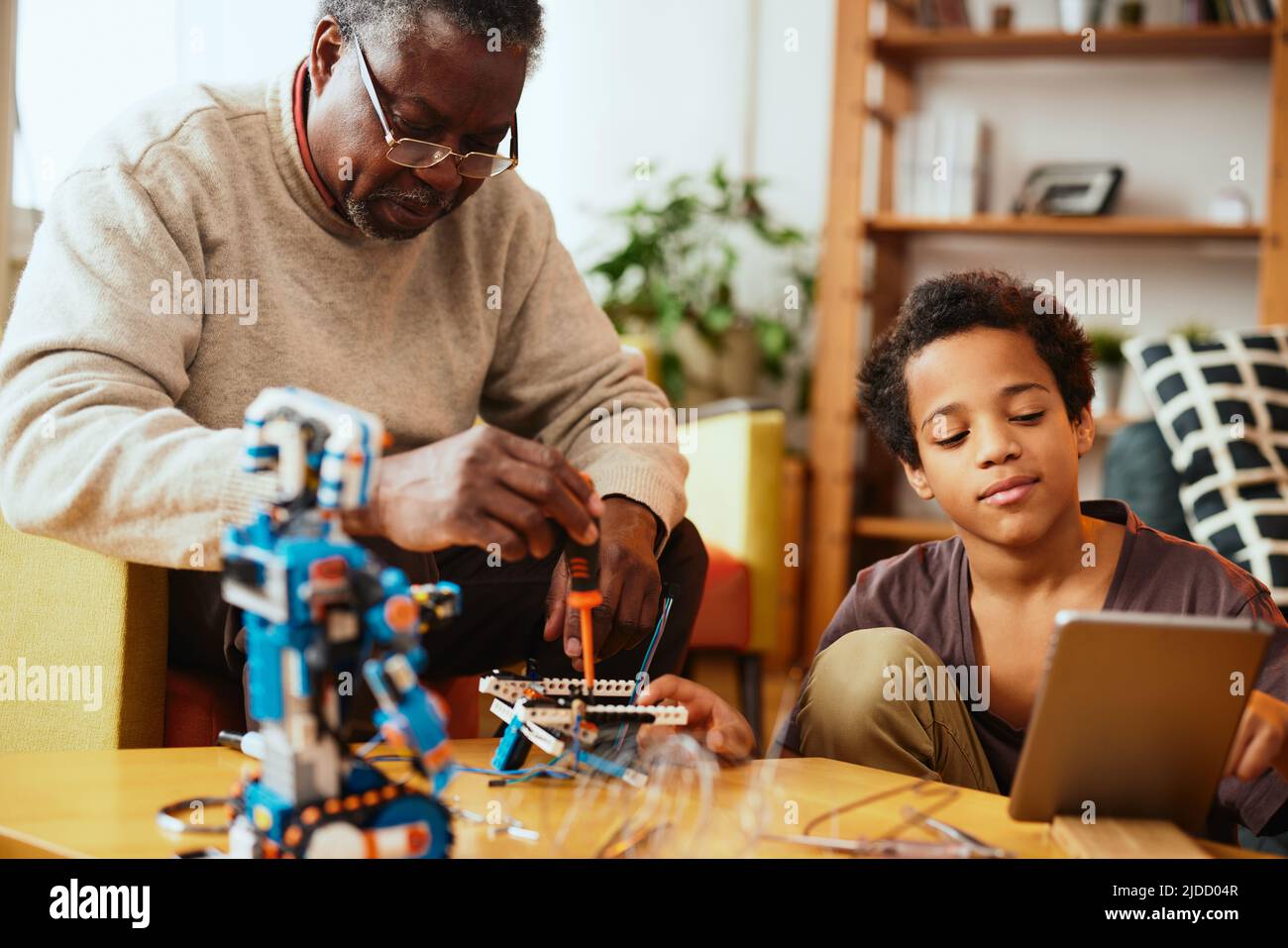 Un nonno e un nipote che fanno insieme un robot a casa. Formazione in robotica ed elettronica. Foto Stock