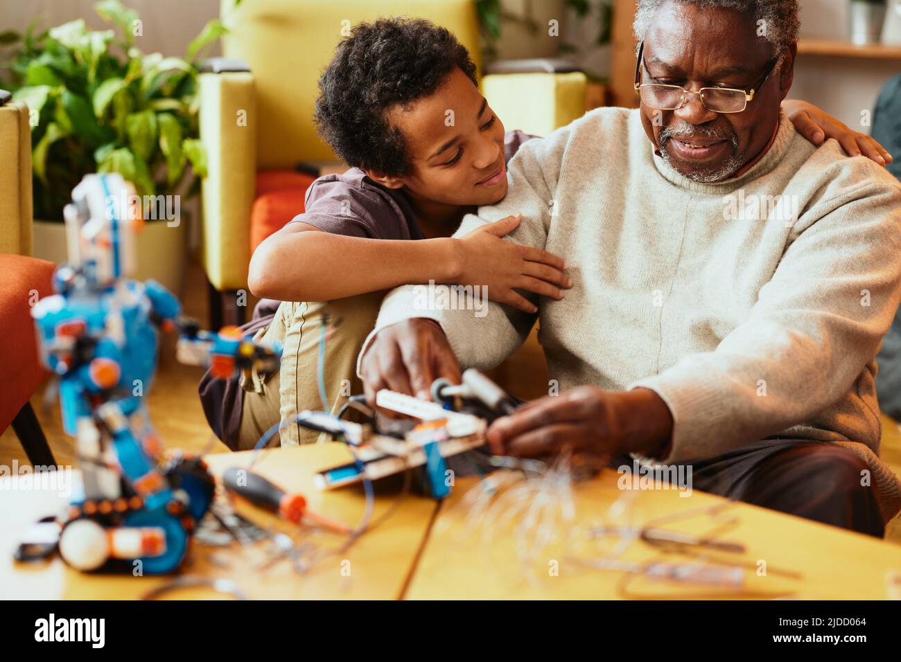 Un nonno e suo nipote costruendo un robot a casa. Foto Stock