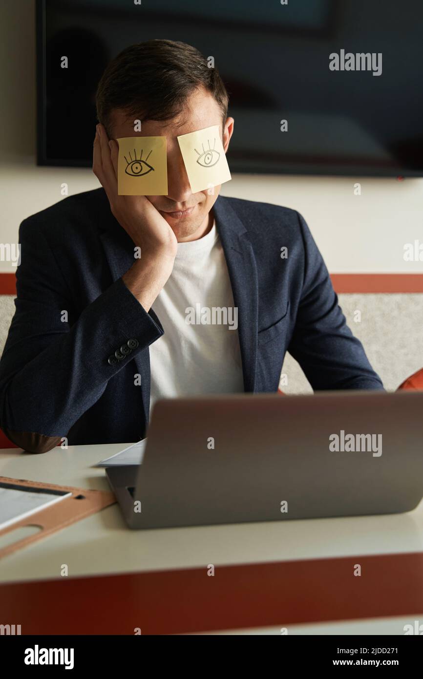 Annoiato lavoratore fotoling intorno con adesivi sugli occhi Foto Stock