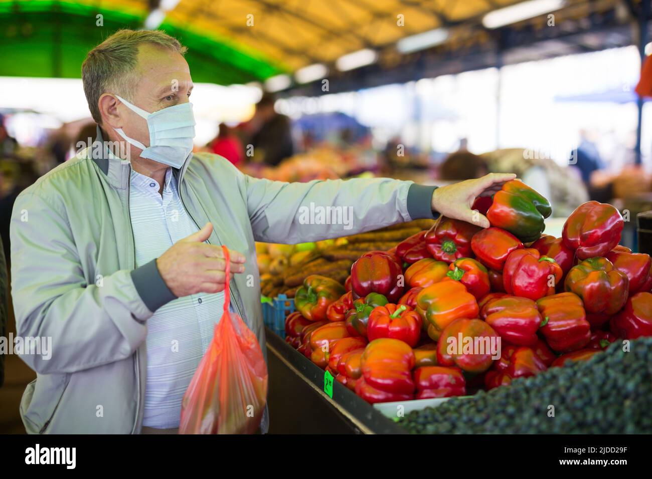 Uomo in maschera acquistare pepe nel mercato Foto Stock