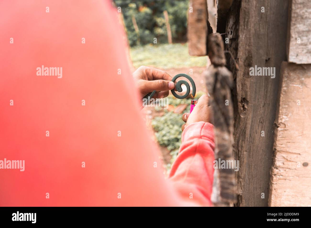 Latino uomo che illumina una bobina di zanzara fuori di una casa Foto Stock