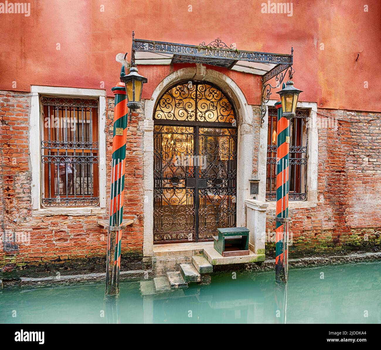 Un pianerottolo privato con tradizionali pali in legno conduce all'ingresso del canale di un hotel a Venezia. Foto Stock