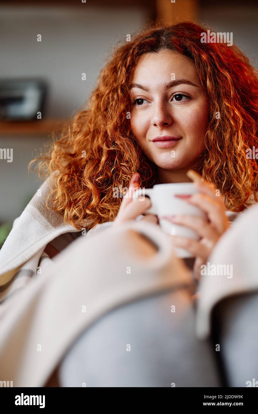 Ritratto di una ragazza zenzero rilassato godendo il suo caffè del mattino in casa accogliente. Foto Stock