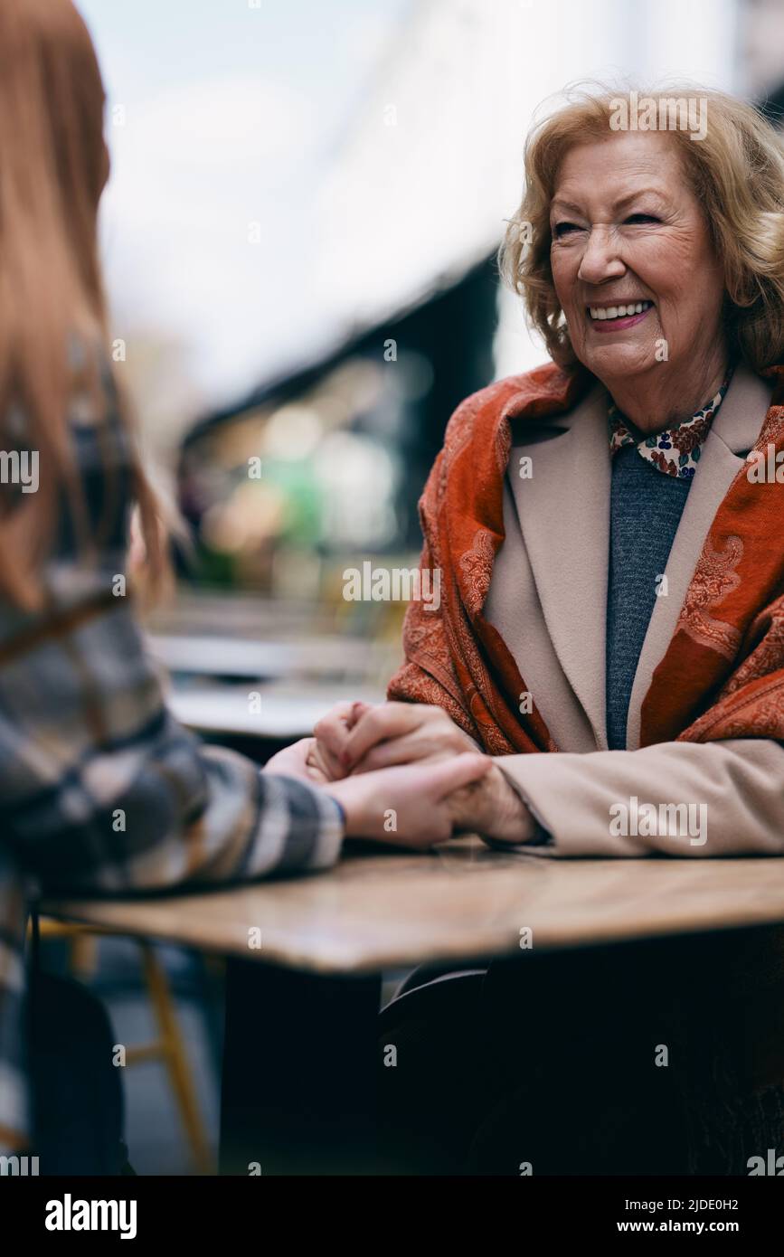 Una nonna che si lega con la nipote mentre si siede in un caffè e tenendo le mani. Foto Stock