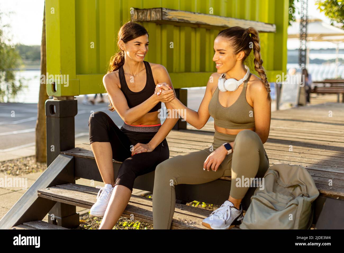 Donne piuttosto giovani in abbigliamento sportivo che si riposano dopo l'esercizio su una passeggiata sul fiume Foto Stock