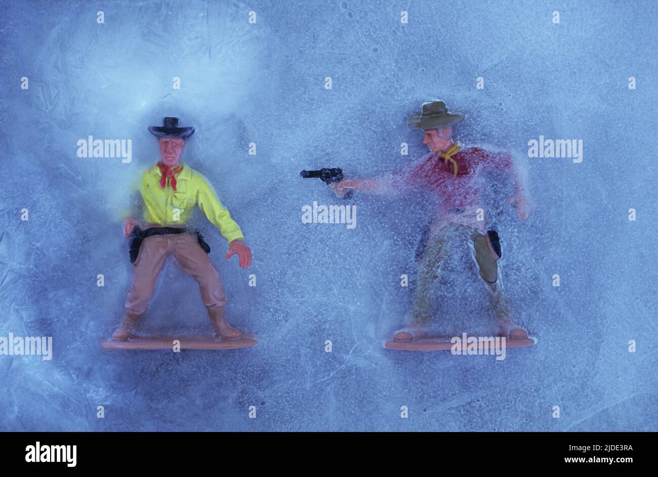 Due modelli in plastica di cowboy in ghiaccio con uno sparare all'altro che sta solo disegnando la sua pistola Foto Stock
