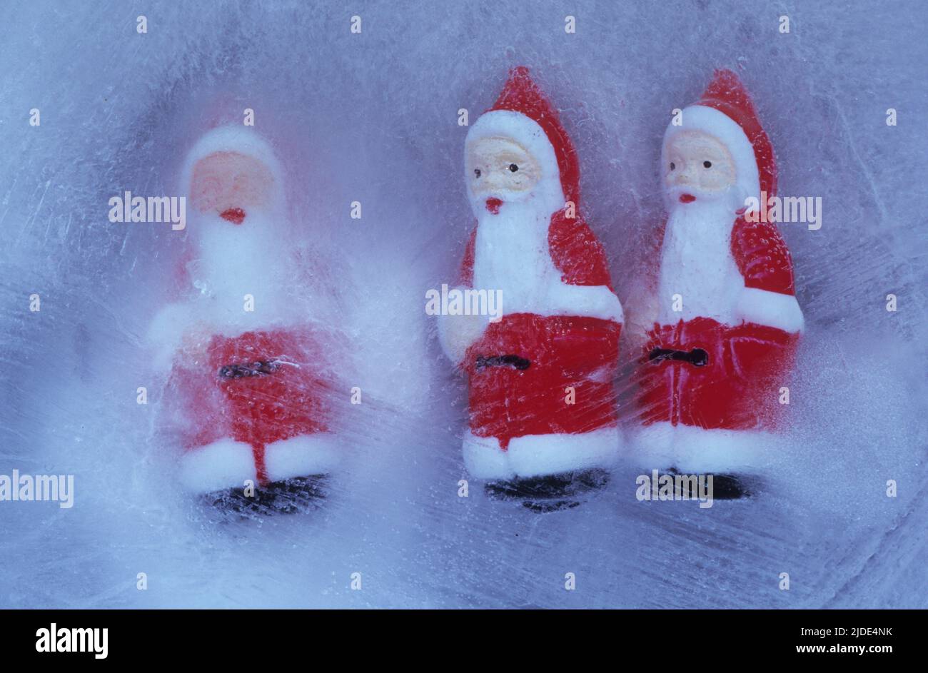 Tre piccoli modelli di Padre Natale in blocco di ghiaccio con due guardando un terzo senza occhi Foto Stock