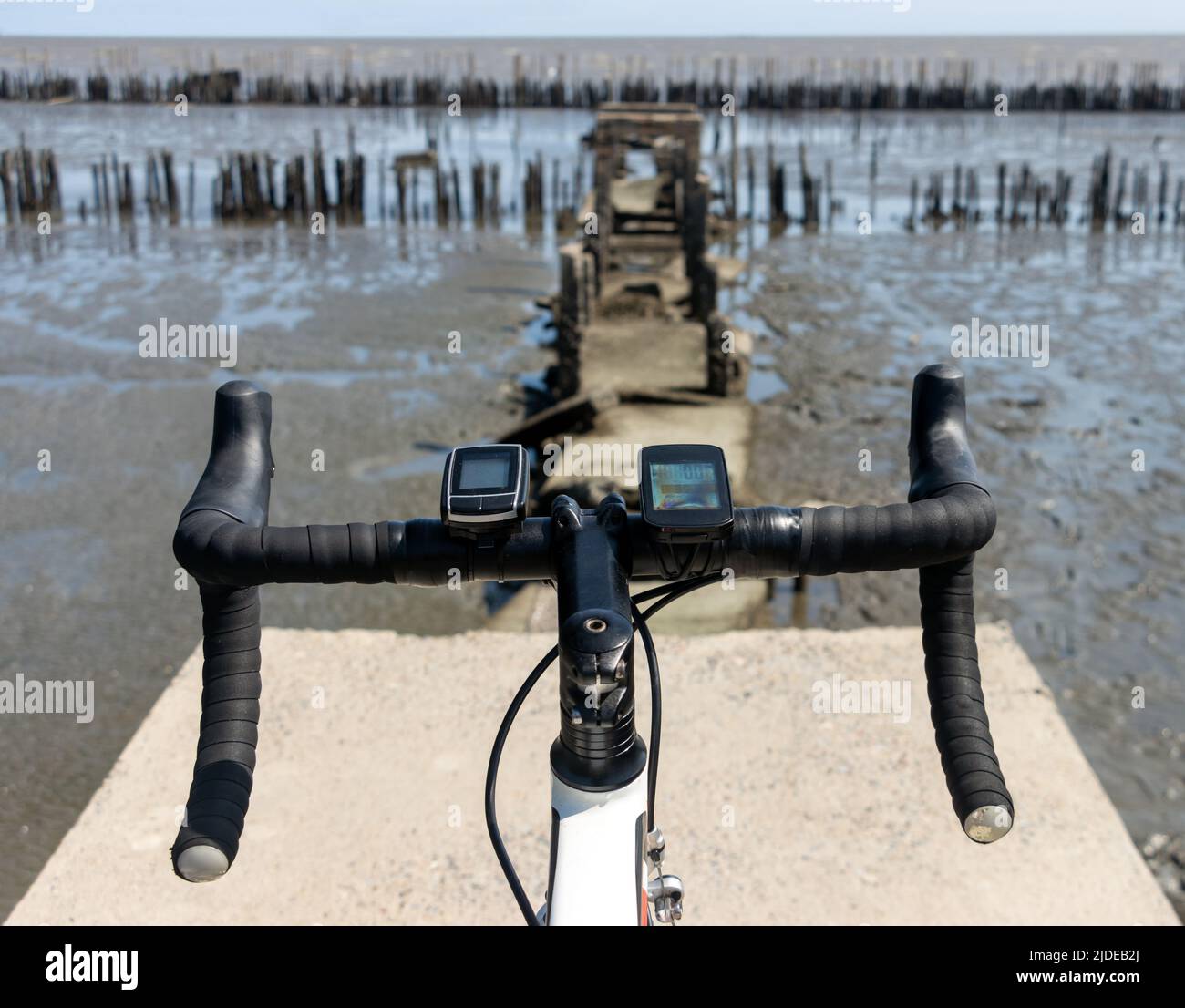 Il manubrio di bicicletta in piedi sul bordo di un modo demolito con orizzonte marino Foto Stock