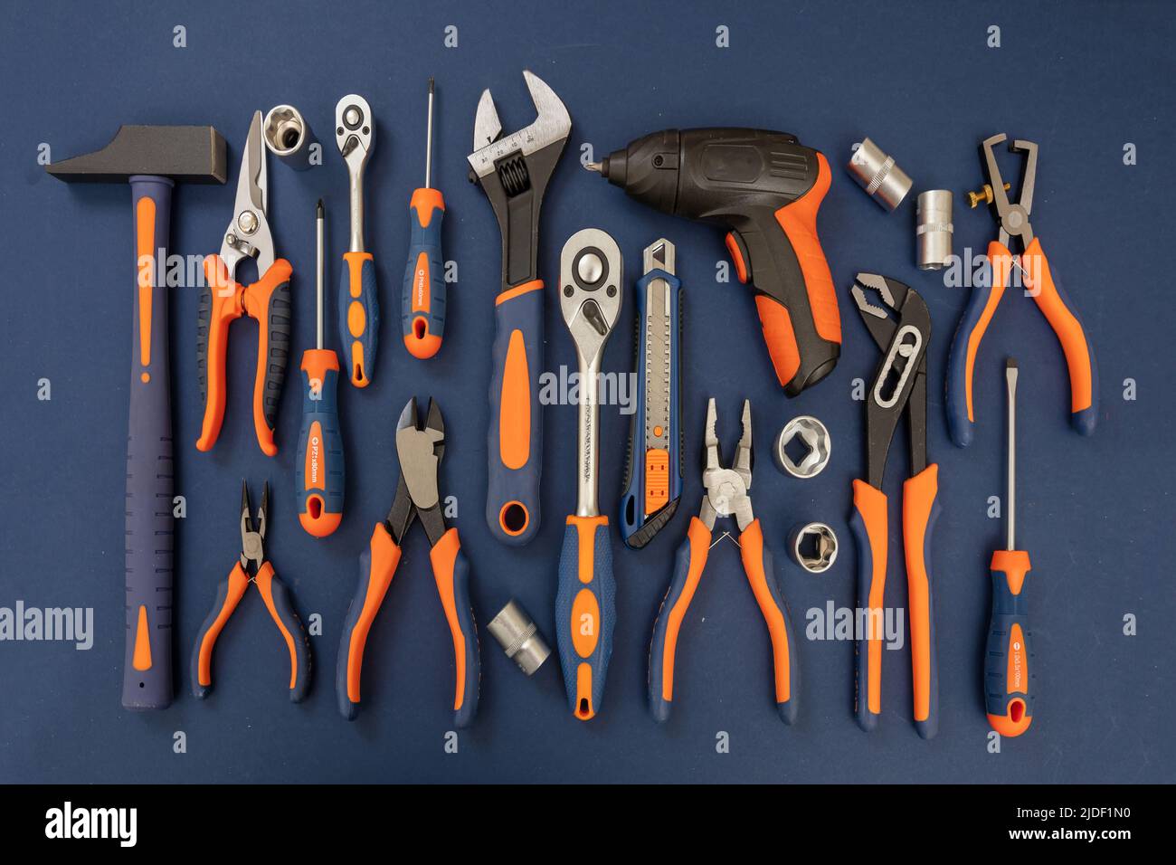 Attrezzatura su sfondo blu. Nuovo set di utensili manuali con manico arancione in gomma per riparazioni e costruzioni, disposizione piatta Foto Stock
