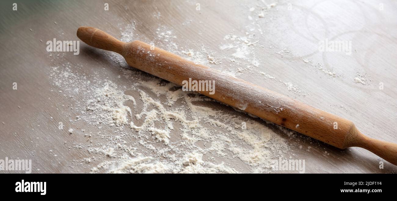 Pasta fatta in casa e preparazione della pasticceria sul tavolo da cucina. Rolling pin, rullo di pasta di legno e farina su legno, vista ravvicinata, spazio copia Foto Stock