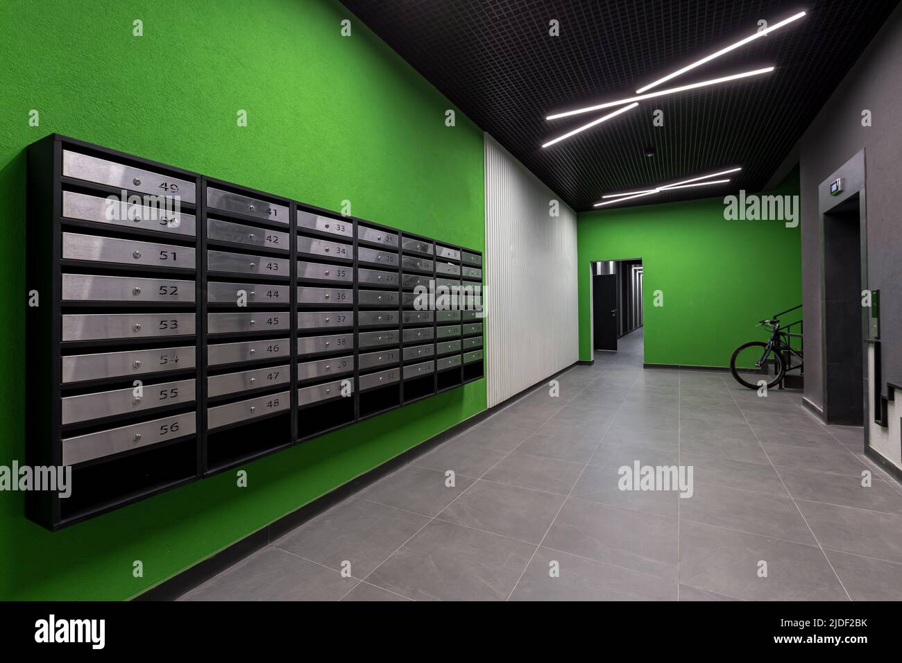 Corridoio interno, con porta d'ingresso e ascensore in molti appartamenti, con cassette postali con pareti verdi Foto Stock