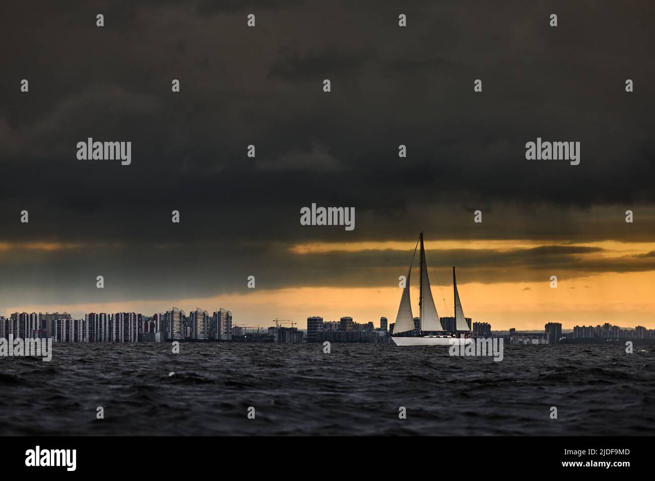 Barca a vela in mare a tempesta, nuvole tempesta cielo arancione, regata vela, riflesso della vela in acqua, bigl onde d'acqua, Foto Stock