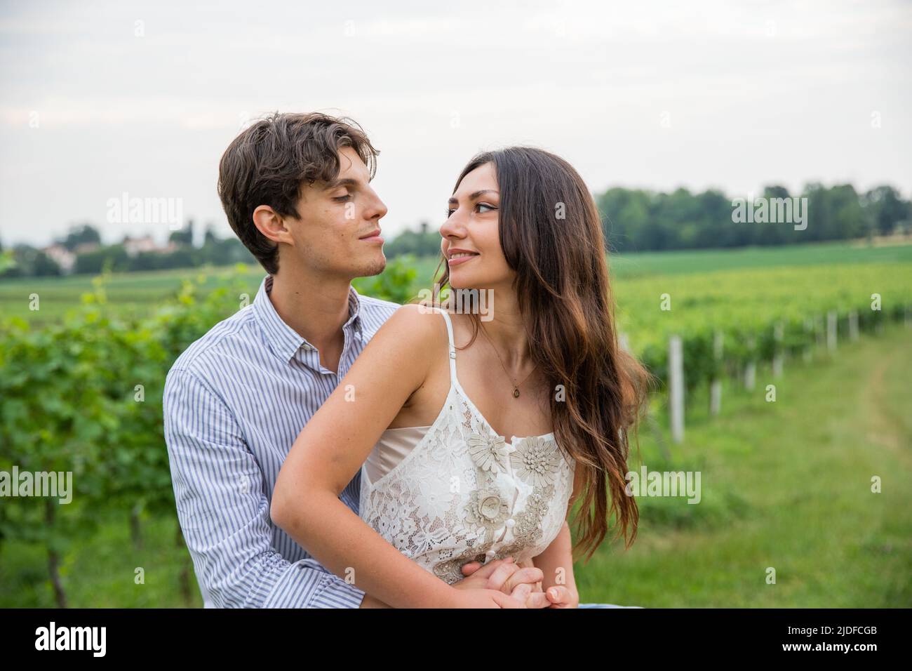 Bella giovane coppia si guarda negli occhi l'uno dell'altro, aggrappandosi nella vigna. Foto Stock