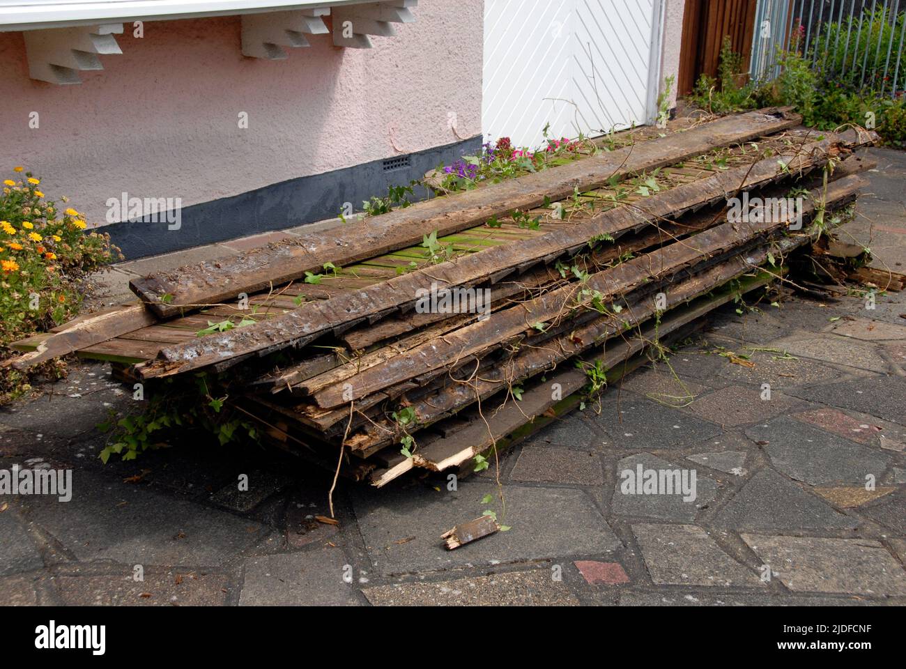 Resti di recinzione di giardino domestico vecchio accatastato di fronte a casa mentre in attesa di raccolta per lo smaltimento Foto Stock