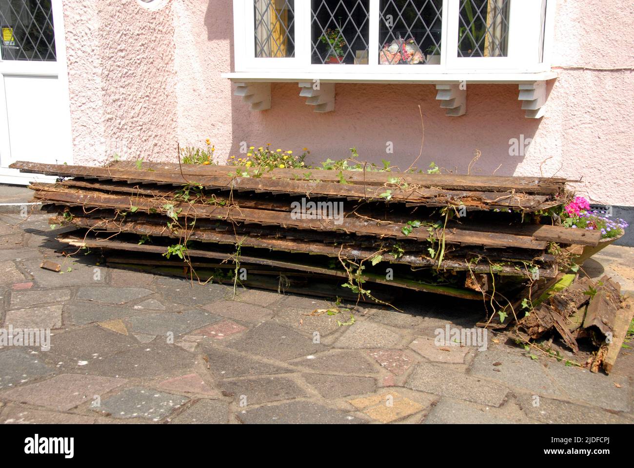 Resti di recinzione di giardino domestico vecchio accatastato di fronte a casa mentre in attesa di raccolta per lo smaltimento Foto Stock