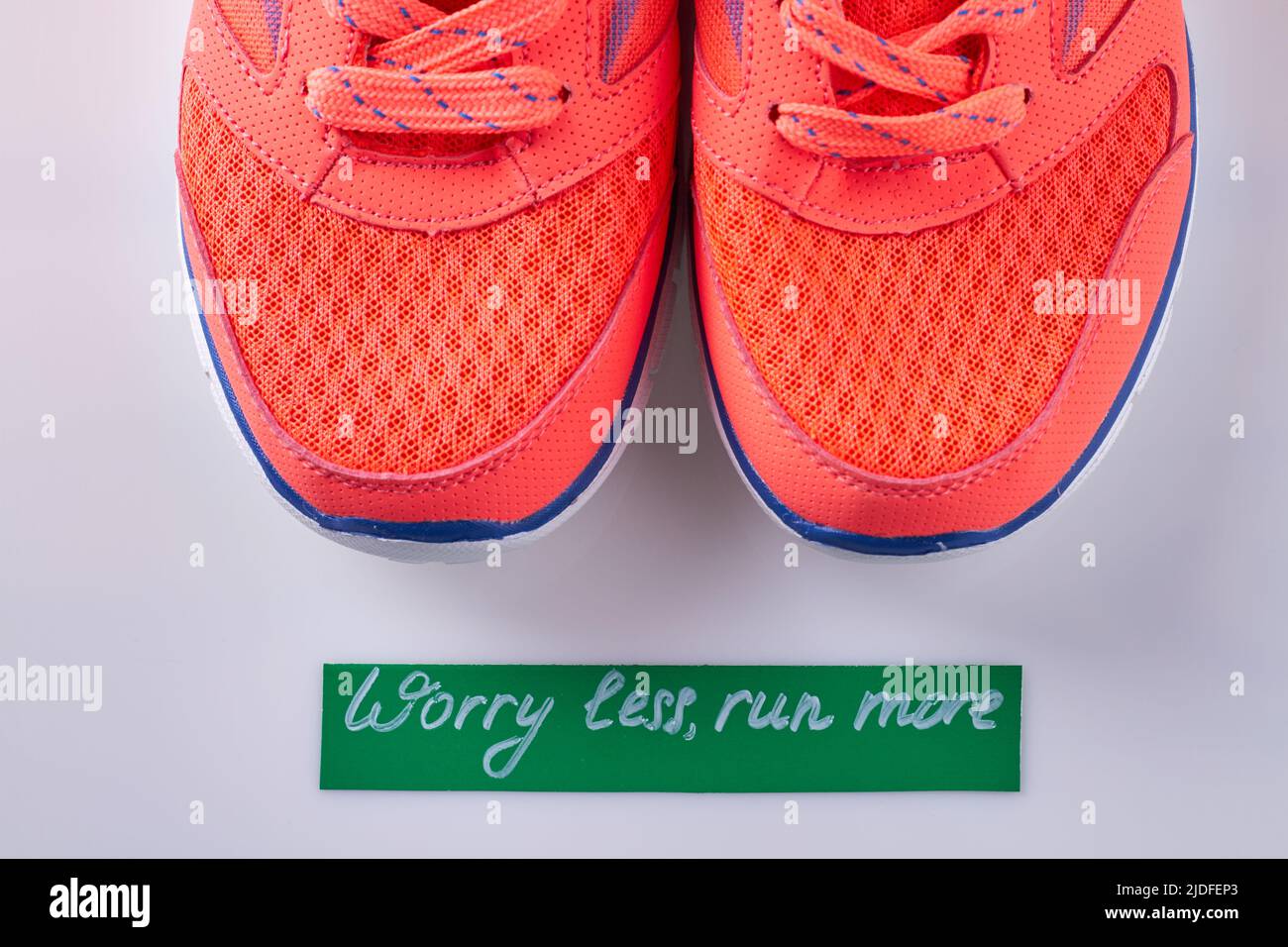 Primo piano paio di scarpe sportive rosse su sfondo bianco. Preoccuparti di meno correre più iscrizione. Foto Stock