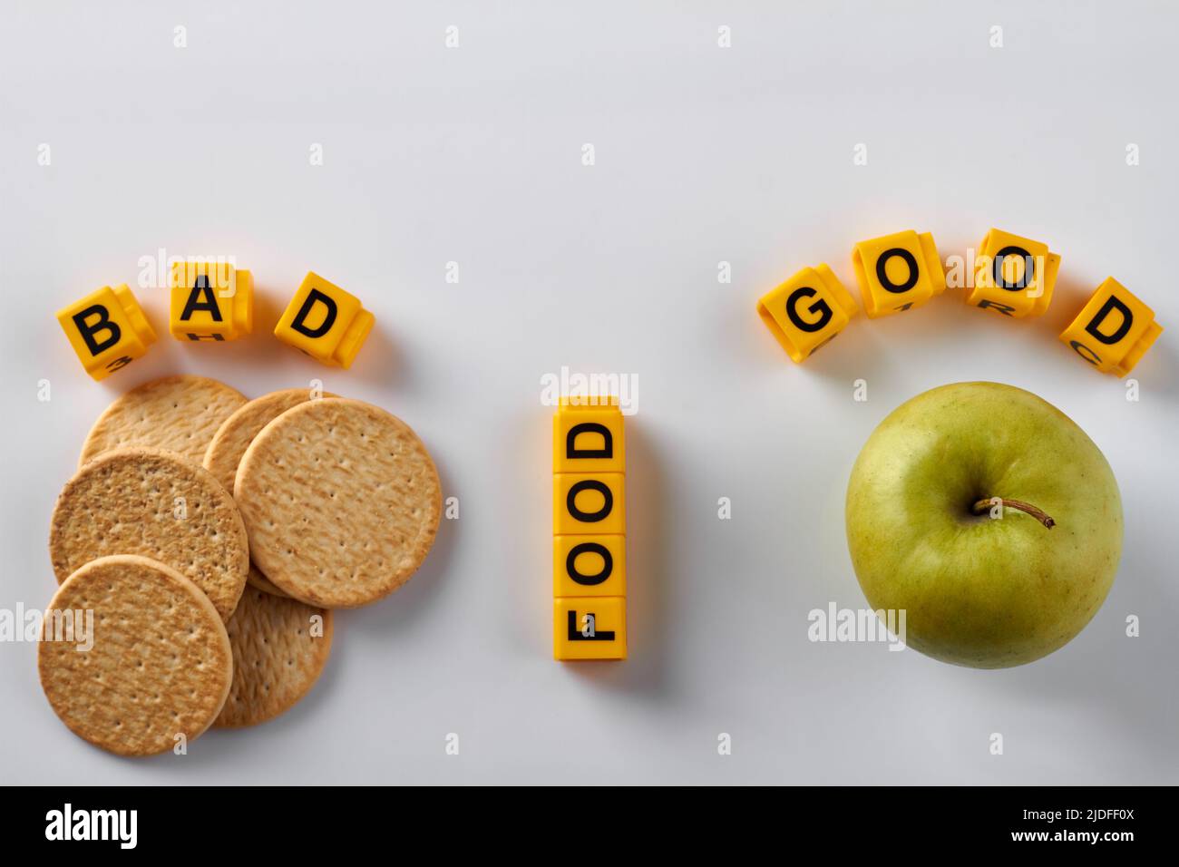 Concetto di piatto di cibo buono e cattivo. Biscotti secchi cracker e mela verde su sfondo bianco. Foto Stock