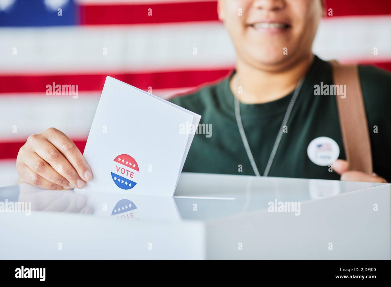 Primo piano di donna mettendo ballottaggio in bin contro sfondo banner USA, spazio copia Foto Stock