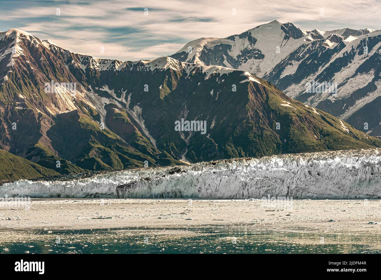 Dischantment Bay, Alaska, USA - 21 luglio 2011: Montagna boscosa verde sul retro del ghiacciaio Hubbard parete di ghiaccio bianco raggiungere l'acqua dell'oceano coperto di ghiaccio Foto Stock