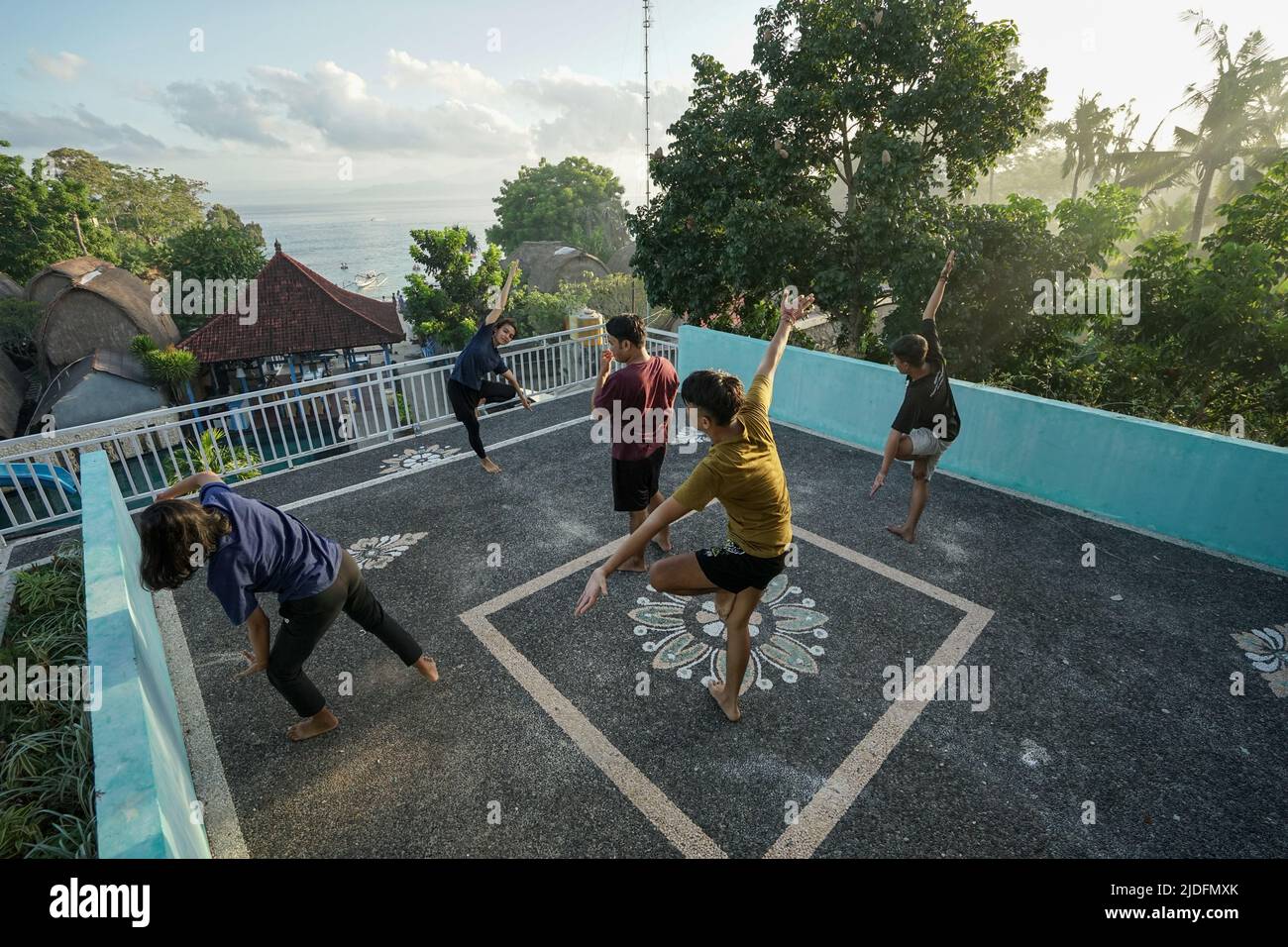 LEMBONGAN, 2 GIUGNO 2022: Cinque giovani praticano lo yoga sul balcone sopra un hotel. La vista di fronte a loro è un mare aperto. Si esercitano o Foto Stock