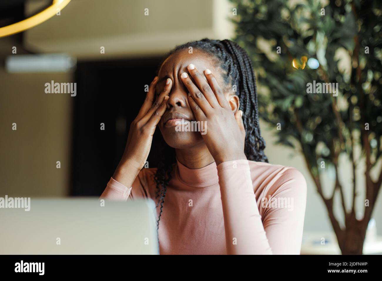 Giovane donna afro americana infelice con paurini che piangono gli occhi coprendo con le mani in chioseup caffè casa. Depressa ragazza nera che soffre, disperata Foto Stock