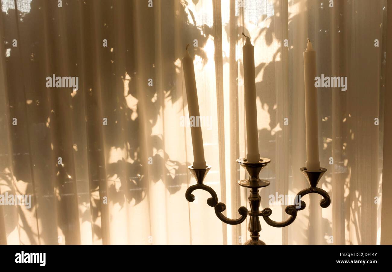 candele in supporto davanti a tende trasparenti e ombre di alberi con spazio di copia Foto Stock