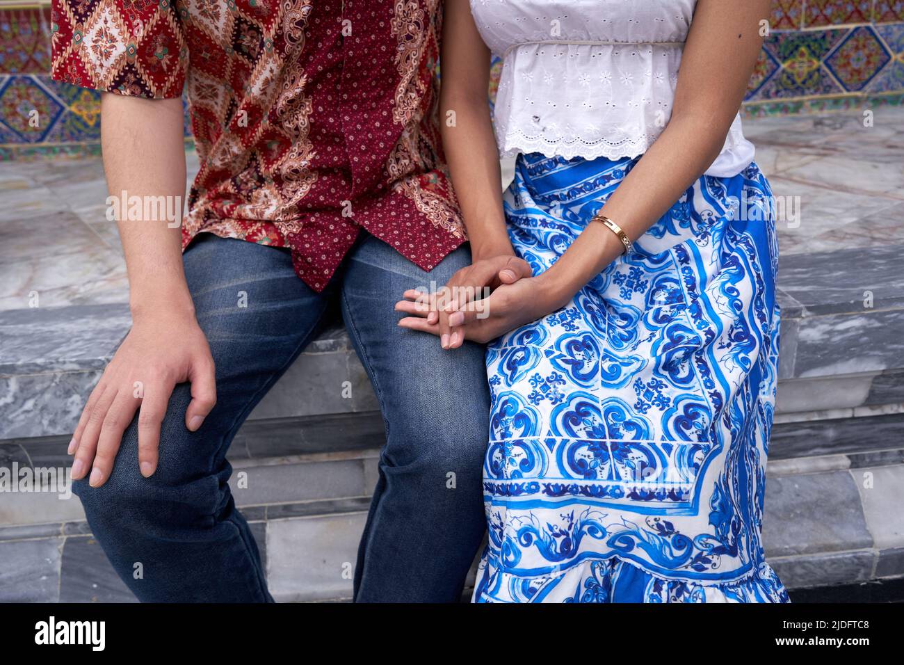 Foto ritagliata di una coppia transgender seduta in scale di un tempio buddista Foto Stock