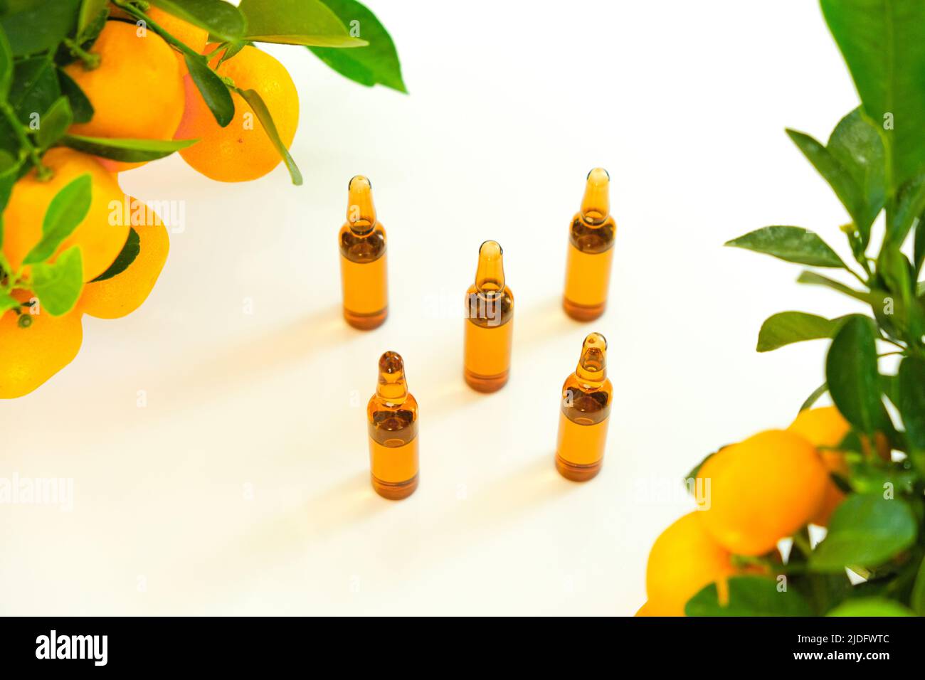 Vitamina C. ampolle di vetro con una soluzione di vitamina C e cespugli di tangerine. Bellezza e salute. Iniezioni di vitamina C, agrumi con verde Foto Stock