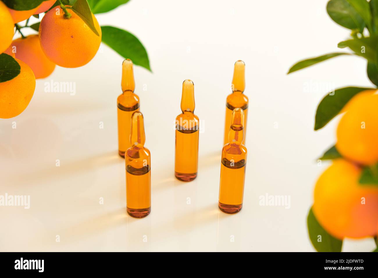 Vitamina C .fiale di vetro marrone con una soluzione di vitamina C e cespugli di tangerine.bellezza e salute. Iniezioni di vitamina C, agrumi con Foto Stock