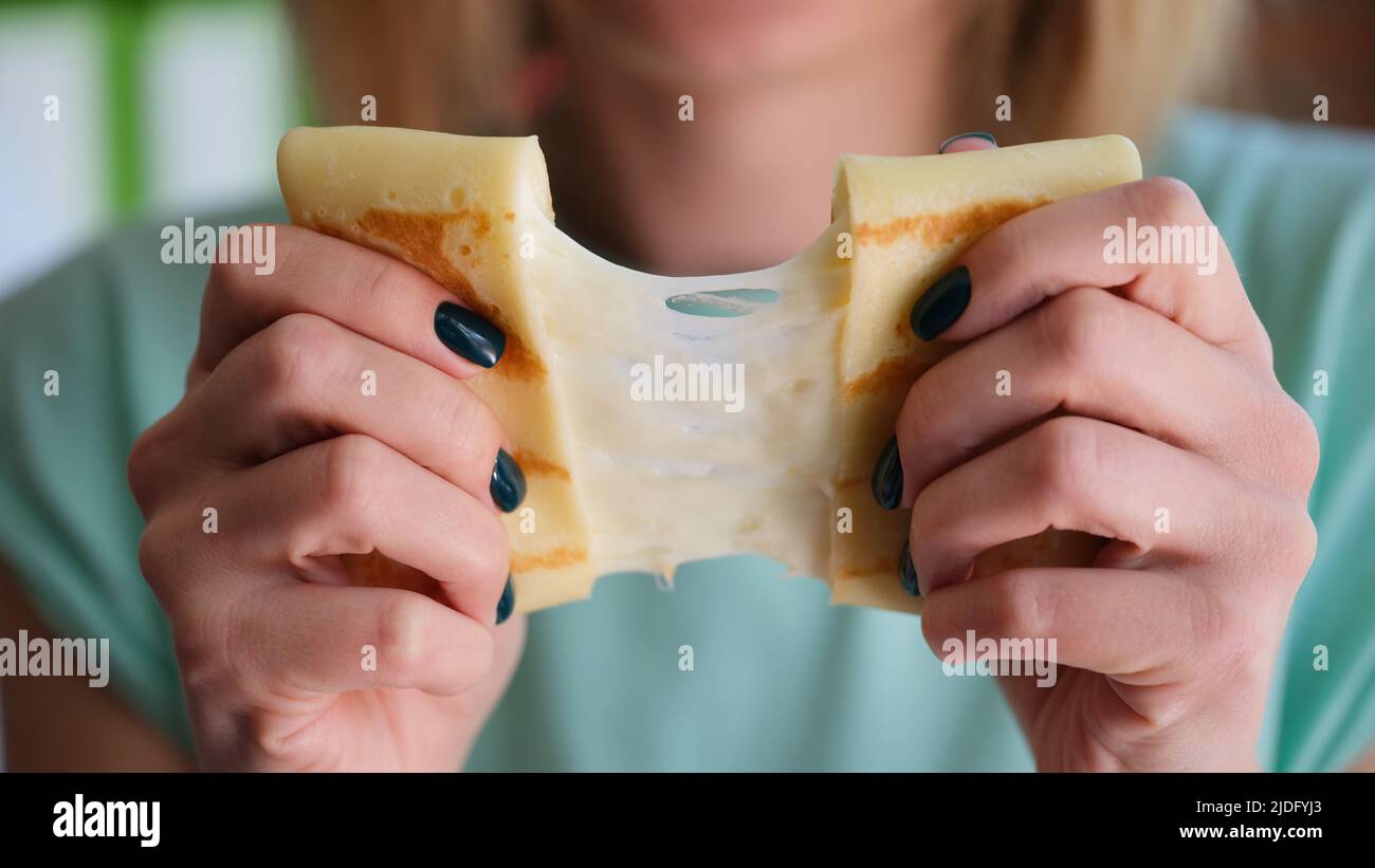 Le mani femminili tengono la frittella con il ripieno di formaggio Foto Stock