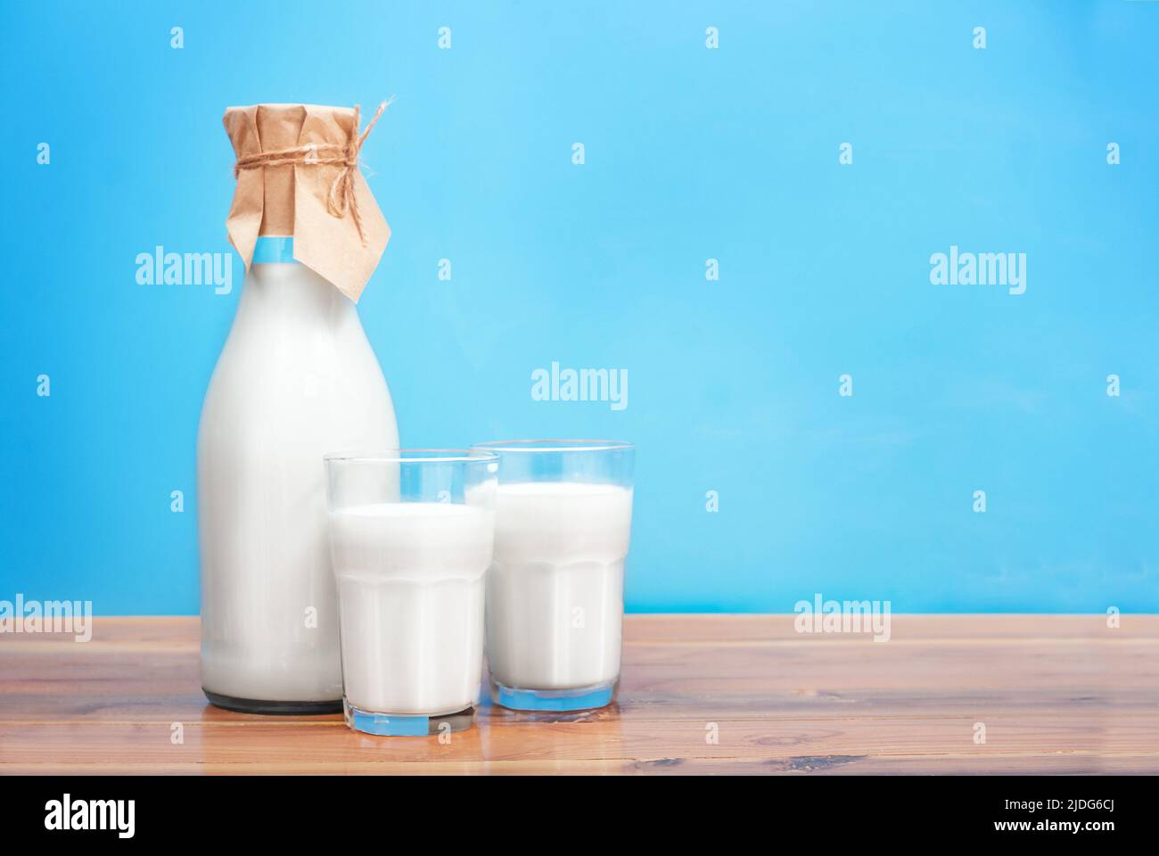Bicchieri e bottiglia con latte fresco su sfondo blu Foto Stock