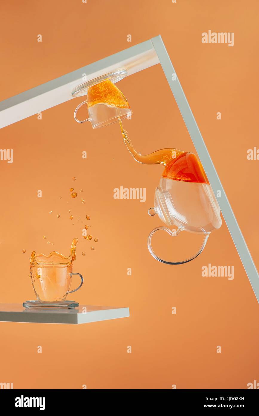 Festa del tè capovolta, splash del tè, tavolozza di arancioni, fotografia creativa delle bevande calde Foto Stock