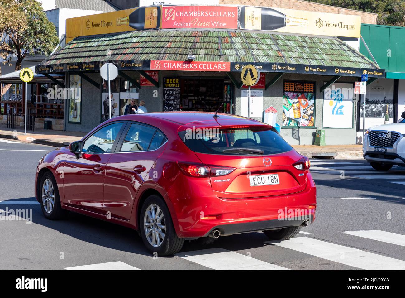 Australian 2017 Mazda 3 auto rossa che passa attraverso zebra pellicano traversata in Avalon Beach, Sydney, Australia Foto Stock