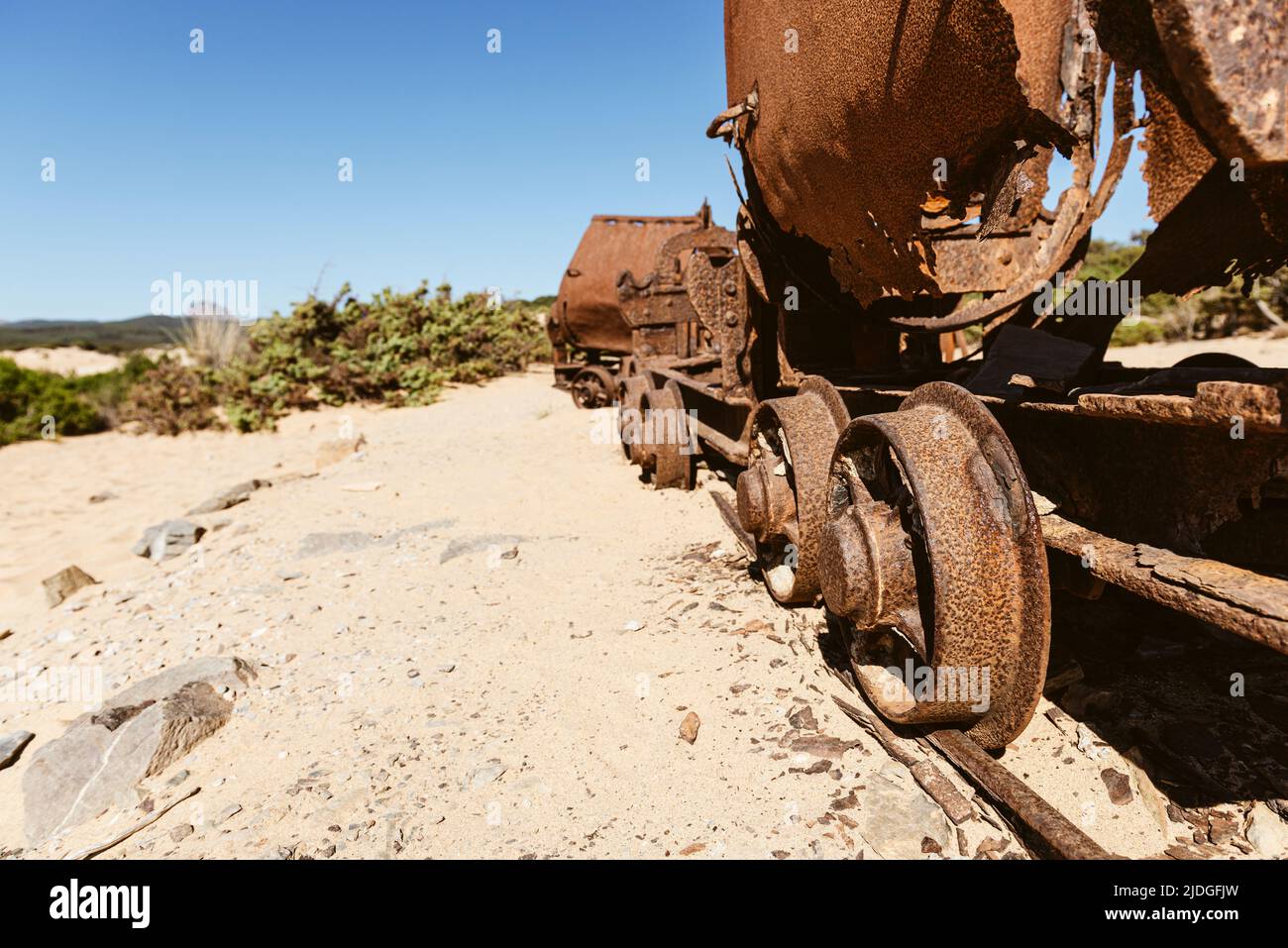 Carri arrugginiti e rottami di una ferrovia dalle miniere di piombo e zinco alle dune di sabbia vicino alla spiaggia di Piscinas, Costa Verde, Sardegna, Italia Foto Stock