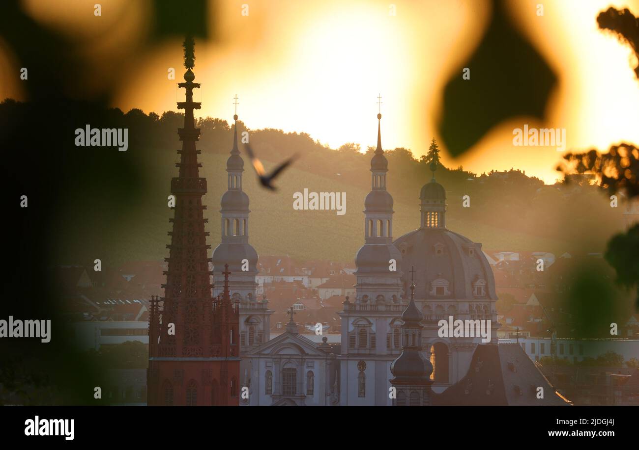 21 giugno 2022, Baviera, Würzburg: Il sole sorge dietro le torri della Cappella della Signora (l) e della Chiesa Stift Haug. Foto: Karl-Josef Hildenbrand/dpa Foto Stock