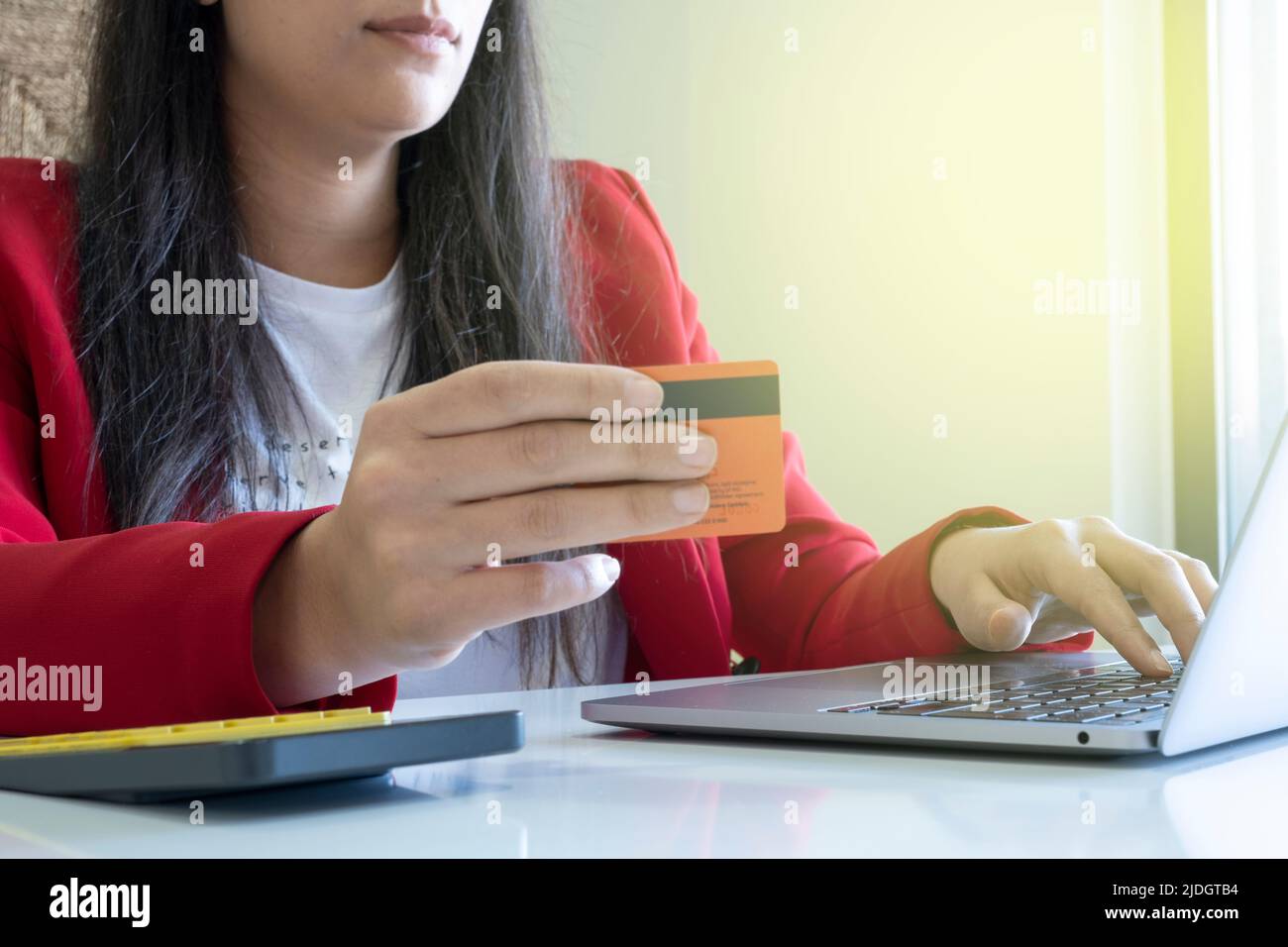 In possesso di carta di credito, giovane donna in possesso di carta di credito e utilizzando il computer portatile. Donna d'affari shopping online in ufficio. Foto Stock