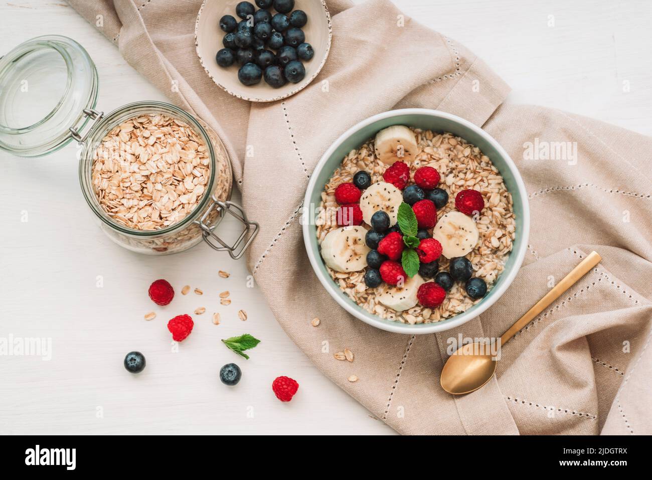 Farinata d'avena fatta in casa con lamponi, mirtilli e semi di chia su tavola bianca. Colazione sana. Vista dall'alto, piatto. Foto Stock