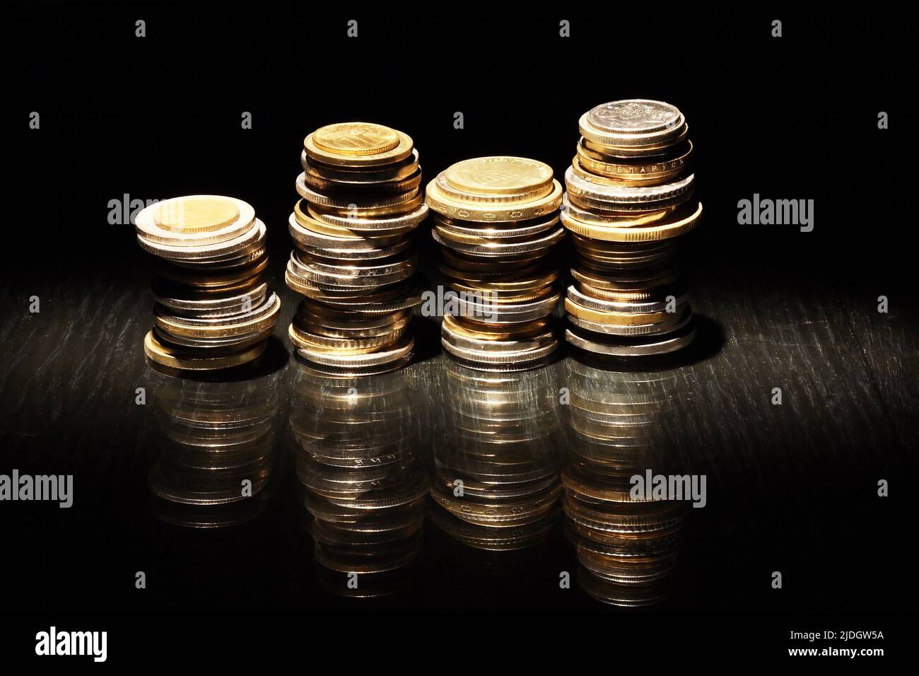 Insieme di monete varie in fila su sfondo scuro Foto Stock