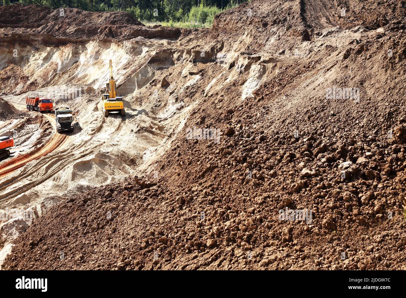 Concetto industriale. Bulldozer e una coda di camion in cava di sabbia Foto Stock