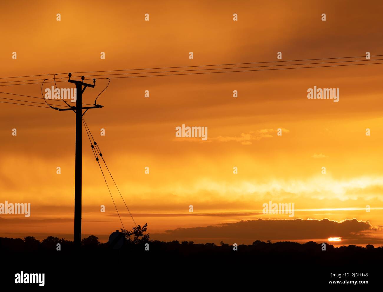 Palo di distribuzione dell'elettricità in legno e cavi al tramonto. REGNO UNITO Foto Stock