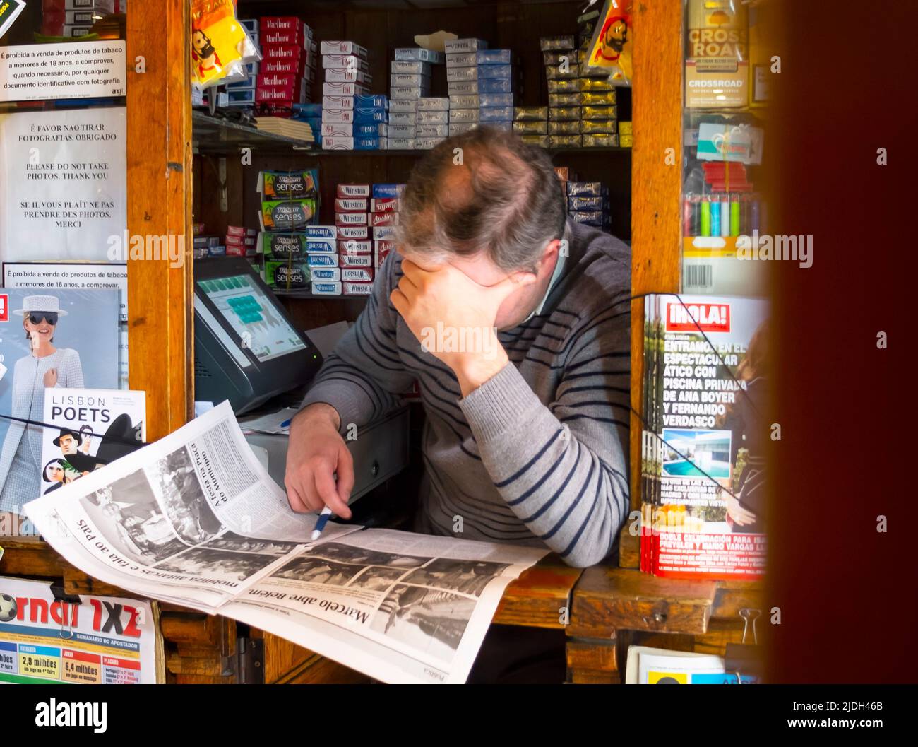 Uomo nel chiosco che legge un giornale, Portogallo, Lisbona Foto Stock